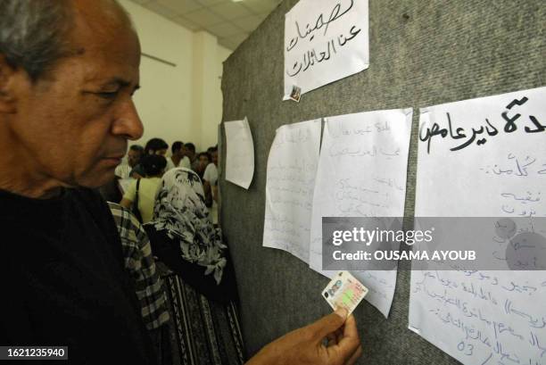 Displaced southern Lebanese man searches for the names and phone numbers of relatives who fled to various areas in Lebanon on lists hung on a board...