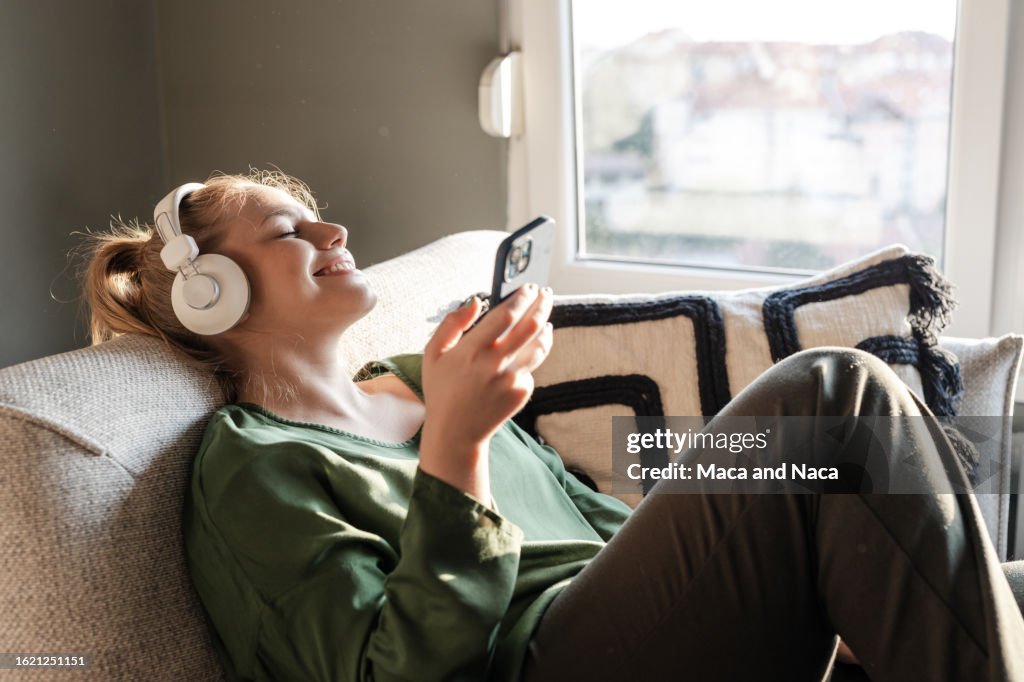 Young woman using music streaming services on her phone