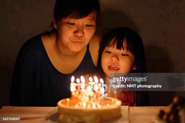 girls blowing birthday cake's candles - parents children blow candles asians foto e immagini stock