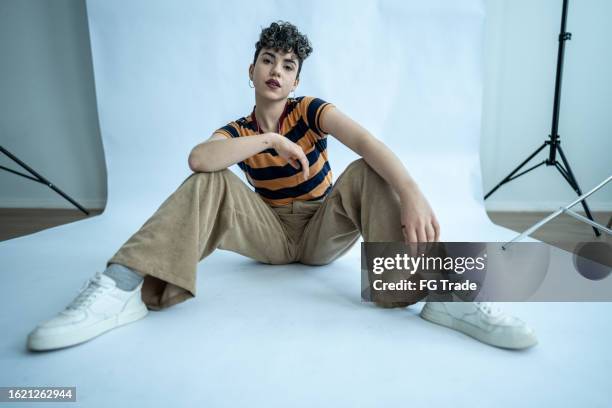 portrait of a young model woman sitting on ground at studio - sitting on ground stock pictures, royalty-free photos & images