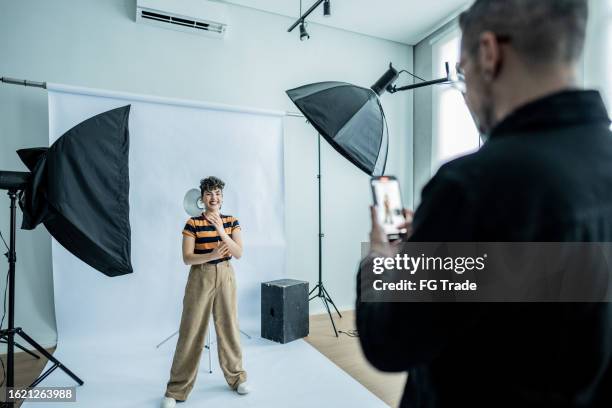 fotograf beim fotografieren/filmen einer jungen modelfrau im studio - fotosession stock-fotos und bilder