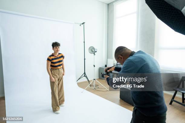 photographer taking photos of a young model woman at studio - photo shoot set up stock pictures, royalty-free photos & images