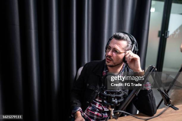mid adult man talking during a interview at podcast - radio broadcasting stock pictures, royalty-free photos & images
