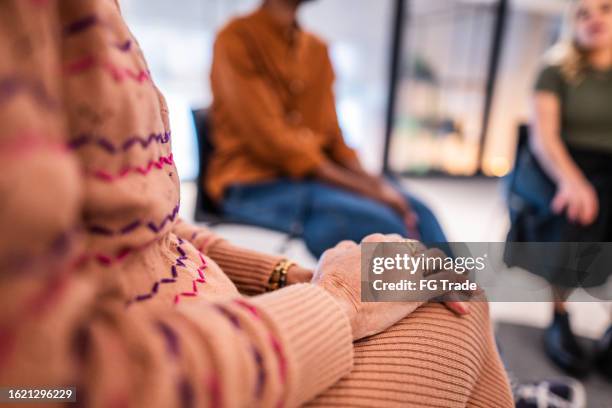 close-up of a senior woman holding her hands during a group therapy - participant stock pictures, royalty-free photos & images