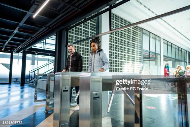 mitarbeiter passieren das drehkreuz am büroeingang - drehkreuz stock-fotos und bilder