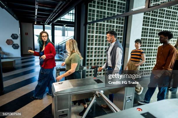 mitarbeiter passieren das drehkreuz am büroeingang - drehkreuz stock-fotos und bilder