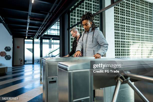 mitarbeiter passieren das drehkreuz am büroeingang - drehkreuz stock-fotos und bilder