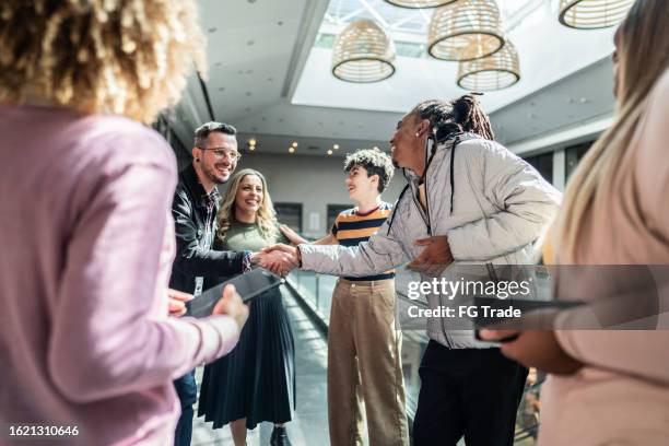 coworkers greeting at office lobby - entering atmosphere stock pictures, royalty-free photos & images