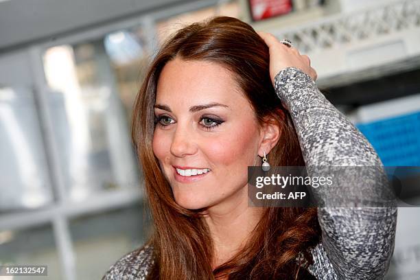 Britain's Catherine, Duchess of Cambridge adjusts her hair during a visit at Hope House charity in south London on February 19, 2013. The Duchess...