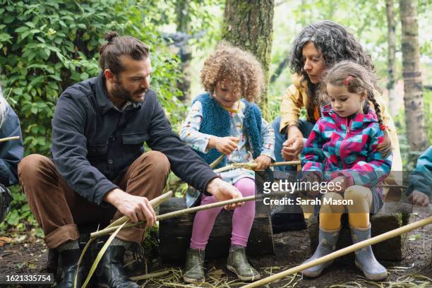 forest school leader shows children and parent whittling sticks - school uk stock pictures, royalty-free photos & images