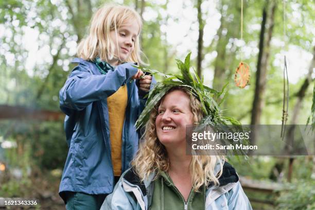 boy adds leaves to mum's leaf crown - plant part stock pictures, royalty-free photos & images