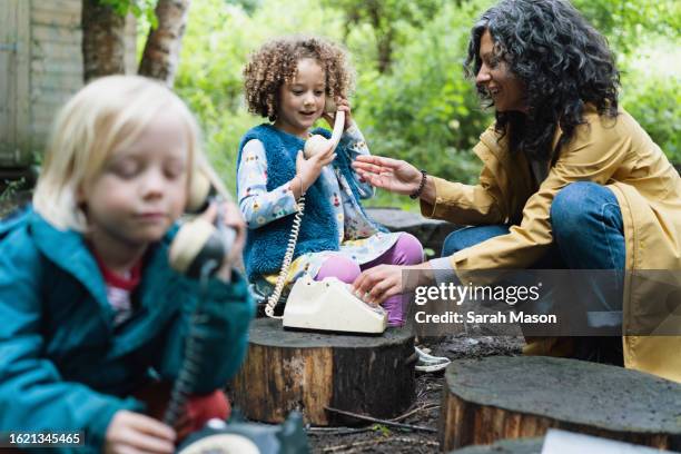 two children talk on old corded phones at forest school - mature man smiling 40 44 years blond hair stock pictures, royalty-free photos & images