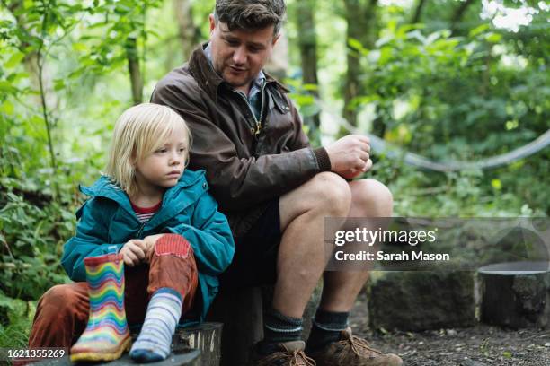 little boy sits with his dad on a tree stump in the woods - plant part stock pictures, royalty-free photos & images