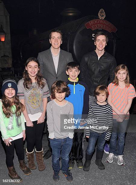 Actors Oliver Phelps and James Phelps pose with fans at The Harry Potter Exhibit at Discovery Times Square on February 19, 2013 in New York City.