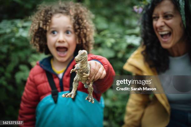 little girl and her mum hold up toy dinosaur and roar - sarah green stock pictures, royalty-free photos & images