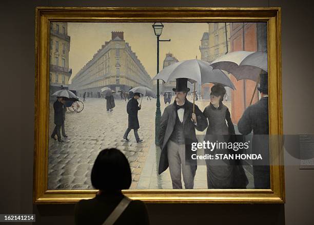 Woman at a media preview looks at "Paris Street; Rainy Day, 1877" by Gustave Caillebotte in the exhibition "Impressionism, Fashion, and Modernity"...