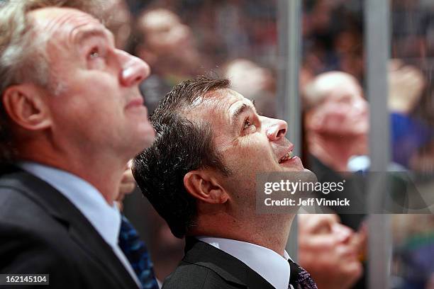 Head coach Alain Vigneault and associate coach Rick Bowness of the Vancouver Canucks smiles look on from the bench during their NHL game against the...