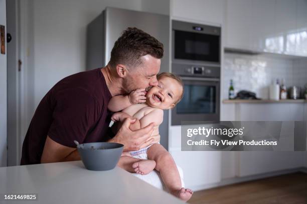 father kisses son on the cheek while feeding him lunch - chinese kissing stock pictures, royalty-free photos & images