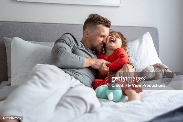 loving father tickles giggling young daughter - tickling stock pictures, royalty-free photos & images