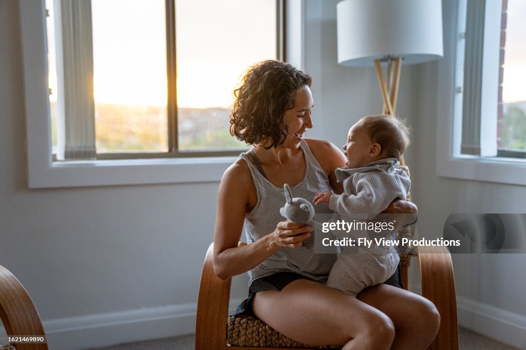 Loving mother plays with baby son in a bedroom