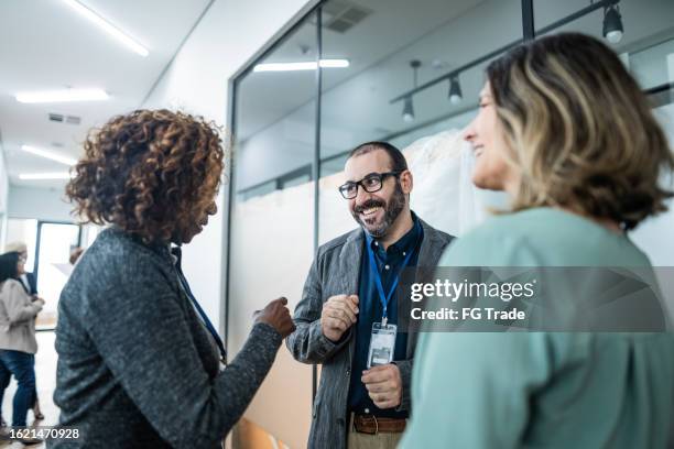 coworkers talking at corridor during a business seminar - mature men office stock pictures, royalty-free photos & images