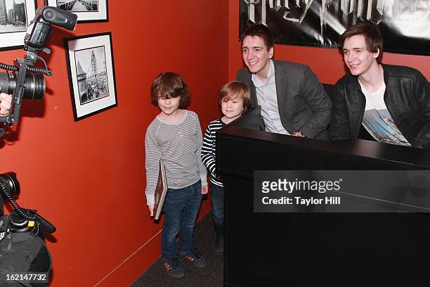 Twin actors Oliver Phelps and Jamie Phelps pose with fans at Discovery Times Square on February 19, 2013 in New York City.