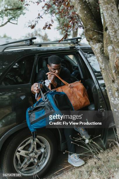 man carries two duffel bags, getting out of a car - duffel tas stockfoto's en -beelden