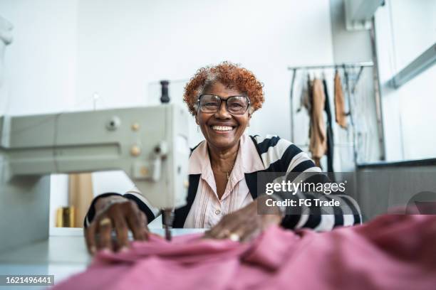 portrait of a senior woman using a sewing machine at atelier - small business stock pictures, royalty-free photos & images