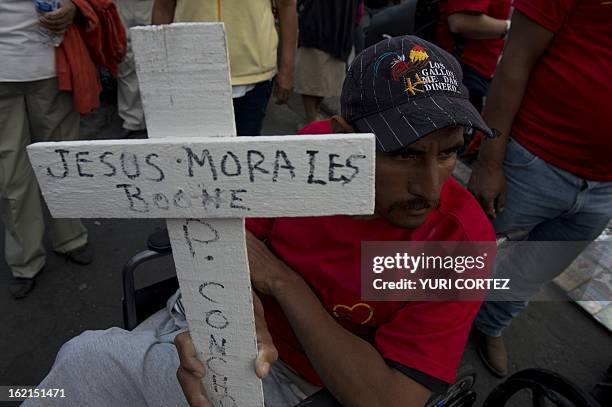 Man holds a cross at El Zocalo square in Mexico City, on February 19 during the commemoration of the 7th anniversary of an accident in which 65...