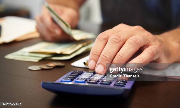 close-up of a person's hand using a calculator and counting money - modulo per la dichiarazione dei redditi foto e immagini stock