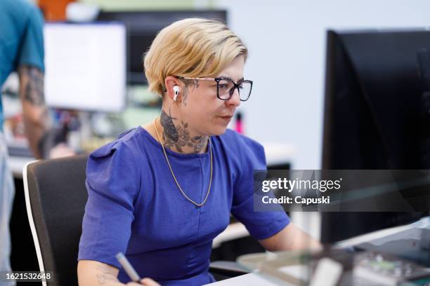 focused designer working with a tablet and wearing earphones - publicidade stock pictures, royalty-free photos & images