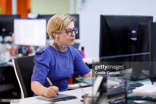 focused designer working with a tablet and wearing earphones - publicidade stock pictures, royalty-free photos & images