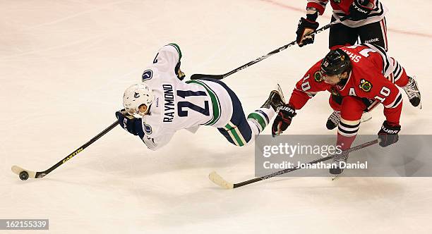 Mason Raymond of the Vancouver Canucks looses his balance as he tries to advance the puck in front of Patrick Sharp of the Chicago Blackhawks at the...