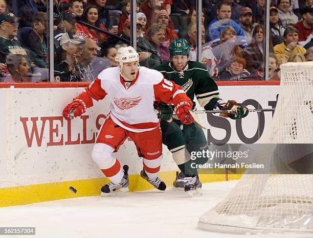 Ian White of the Detroit Red Wings and Jason Zucker of the Minnesota Wild go after the puck during the game on February 17, 2013 at Xcel Energy...