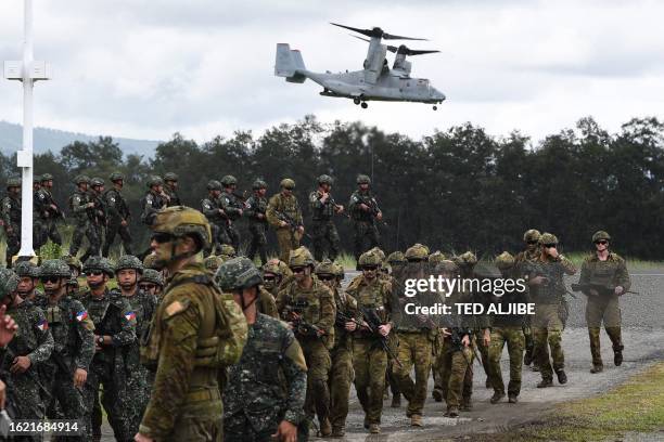 Philippine and Australian soldiers march in formation while a US marines V-22 Osprey hovers above during military exercise Alon , a joint amphibious...
