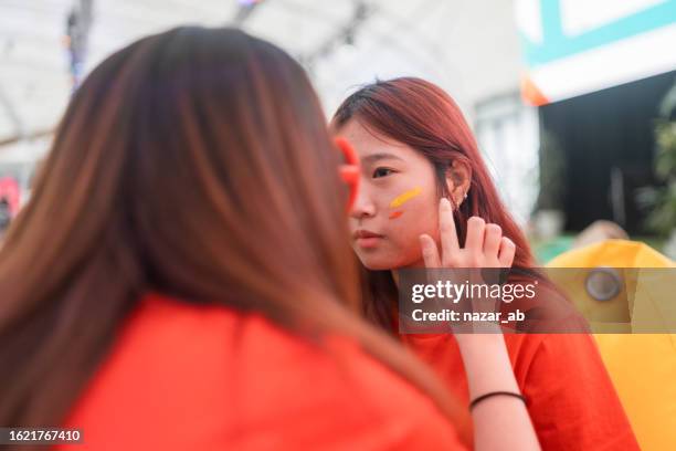 soccer fan putting face paint on getting ready for game. - body paint stock pictures, royalty-free photos & images