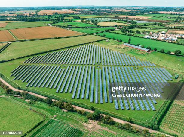 aerial view of solar panels on green field at suburb in sunny day - solar powered station stock pictures, royalty-free photos & images