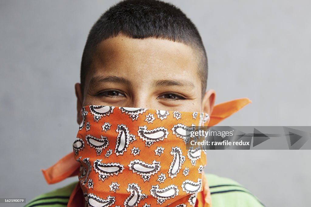 Mexican kid wearing a handkerchief over his mouth.