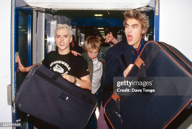 British boy band Busted run through a corridor backstage at TV show CD: UK, London, 2002. Left to right: Mattie Jay, James Bourne and Charlie Simpson.