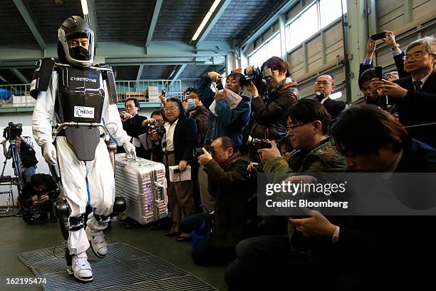 Man, left, demonstrates the Hybrid Assistive Limb work-assist robot suit, developed by Cyberdyne Inc. In the New Energy and Industrial Technology...