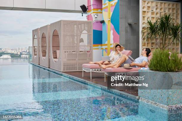 asian couple chatting and enjoying each others company at hotel pool - the weekend in news around the world imagens e fotografias de stock