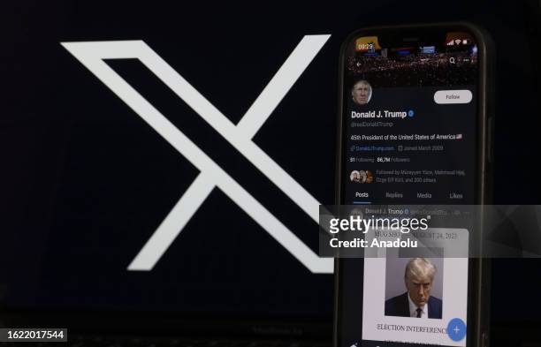 In this photo illustration, the mugshot of Former U.S. President Donald Trump is displayed on a smartphone shared on his X account and the logo of X...