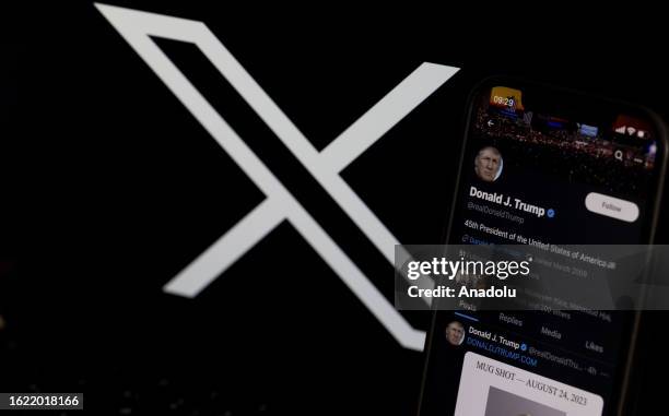 In this photo illustration, the mugshot of Former U.S. President Donald Trump is displayed on a smartphone shared on his X account and the logo of X...