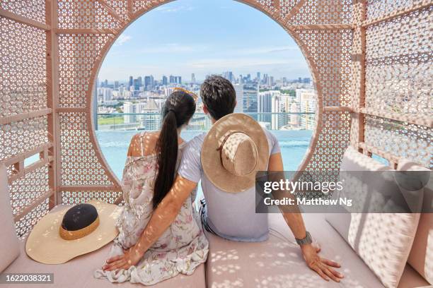 asian couple relaxing in a cabana by hotel pool - luxury city break stock pictures, royalty-free photos & images