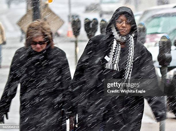 Pedestrians make their way to work through the snow in downtown Wichita, Kansas, Wednesday, February 20, 2013.