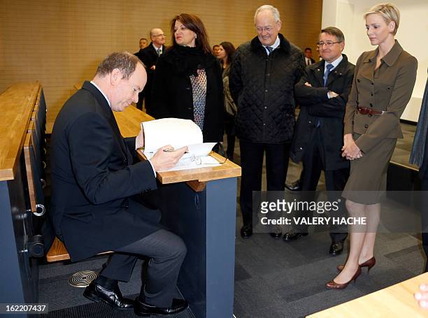 Prince Albert II of Monaco sits in a seat in a classroom as he and Princess Charlene visit the new "Lycee Technique et Hotelier de Monaco" on...