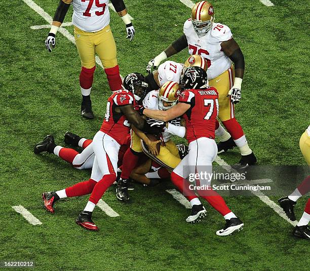 Quarterback Colin Kaepernick of the San Francisco 49ers is tackled by Kroy Biermann and Stephen Nicholas of the Atlanta Falcons during the NFC...