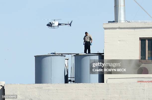 Worker stands on a water tank on the roof of the Hotel Cecil in Los Angeles California February 20, 2013. The body of 21-year-old Canadian tourist...