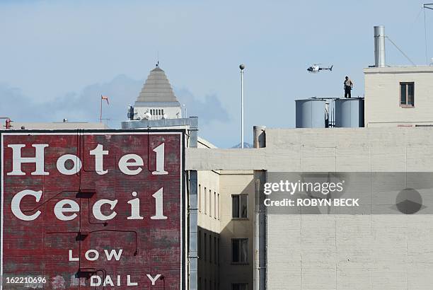 Worker stands on a water tank on the roof of the Hotel Cecil in Los Angeles California February 20, 2013. The body of 21-year-old Canadian tourist...