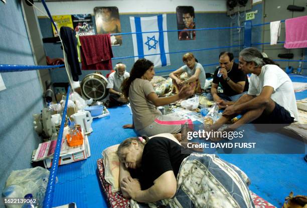 An Israeli woman sleeps and others eat in a boxing ring set up in a bomb shelter, in the northern Israeli city of Nahariya, 13 August 2006. More than...